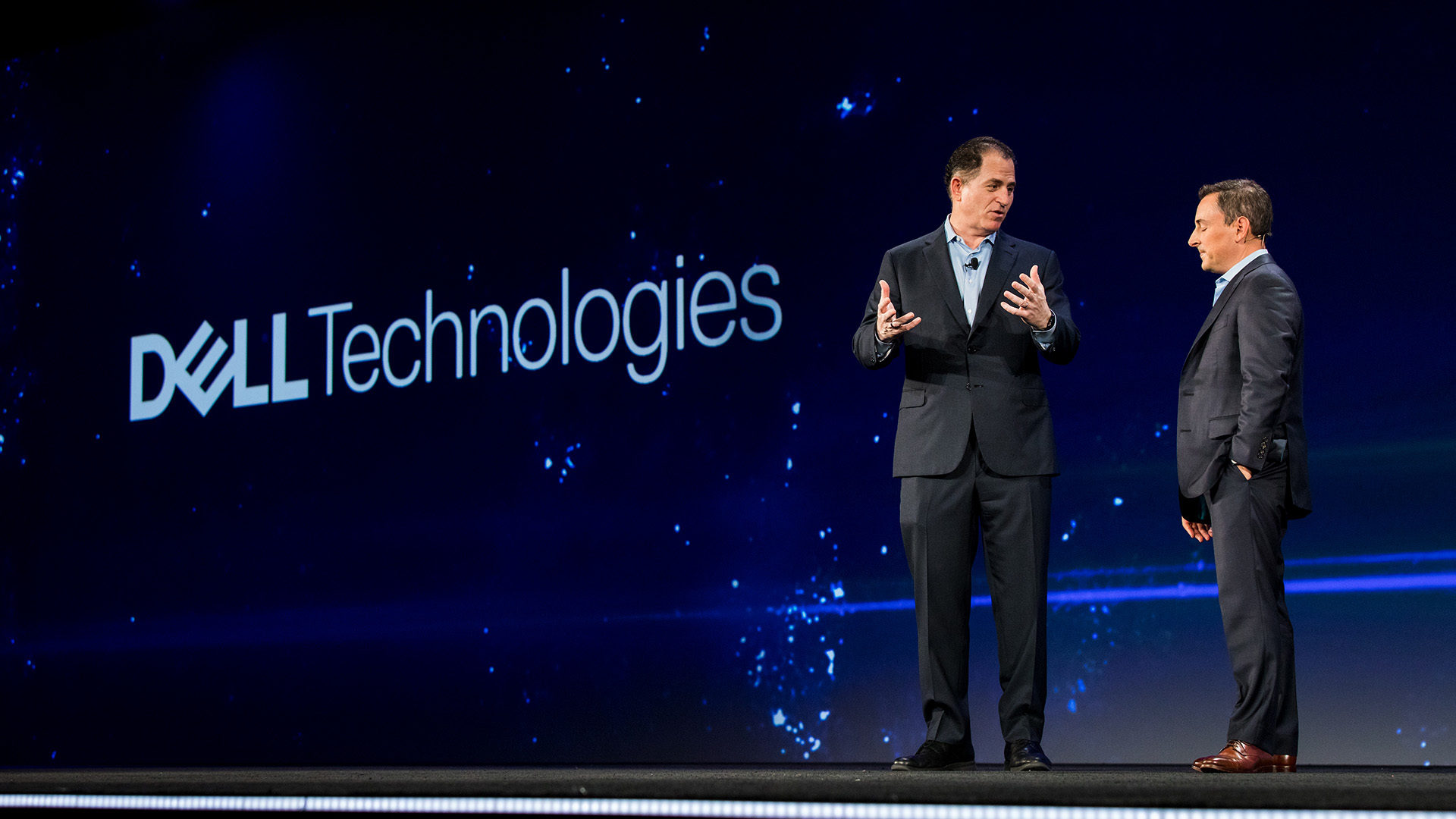 Two men speaking on stage with the Dell Technologies logo on the screen behind them.